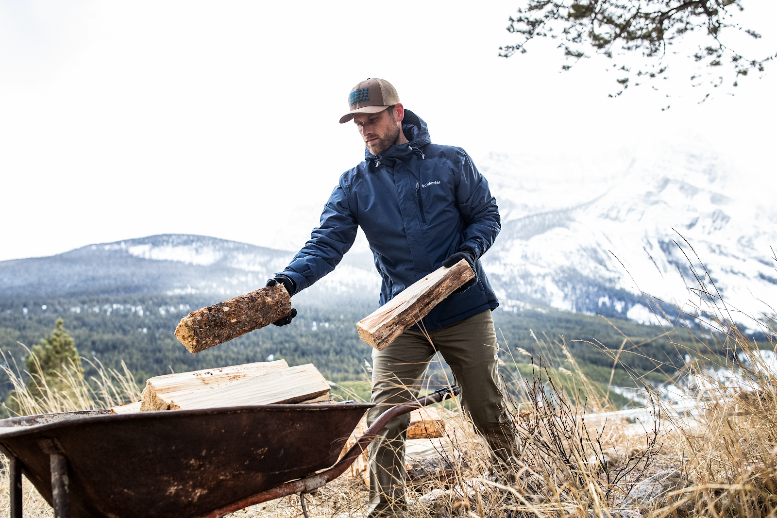 DicksSG Man in Columbia jacket collecting wood with mountain in background.