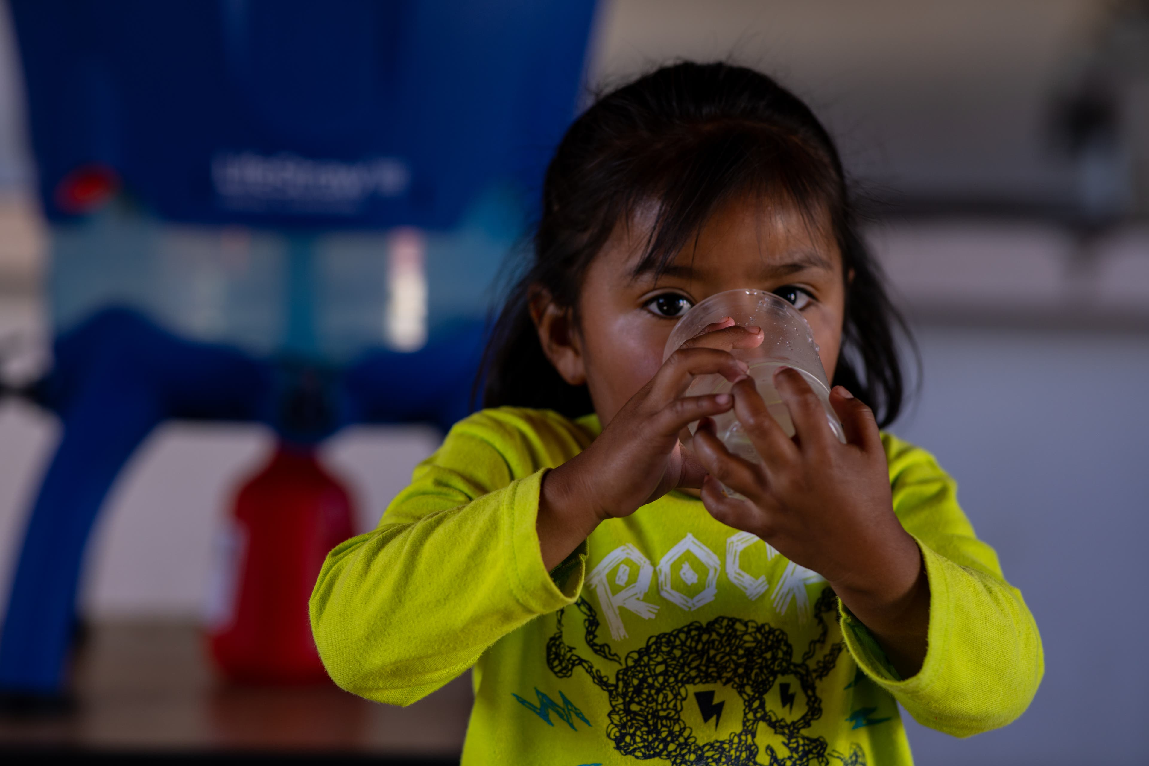DSC09635 Young Tarahumara indian girl in a yellow shirt drinks clean filtered water. Lifestraw filter is out of focus in the background.