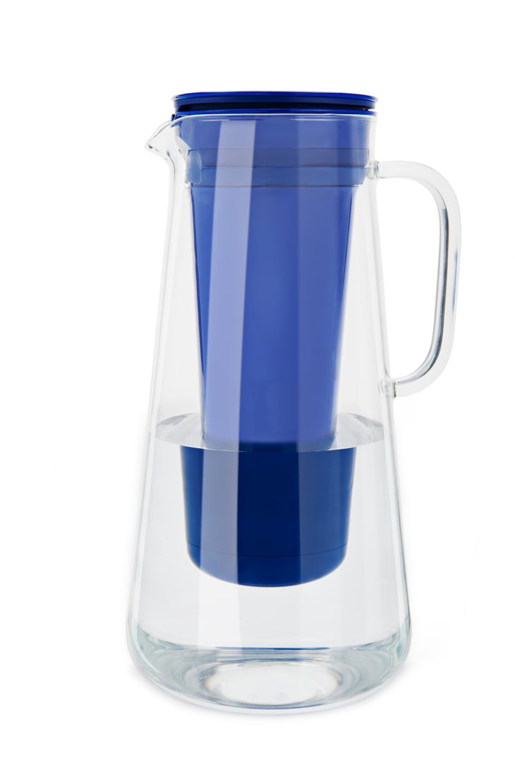 LifeStraw-Home_Glass_Cobalt-Blue_Studio-Single-Shot-With-Water_31 LifeStraw Home water pitcher sits on a white background. The tall clear cone-shaped pitcher has a royal blue conical filter that acts as a lid and…