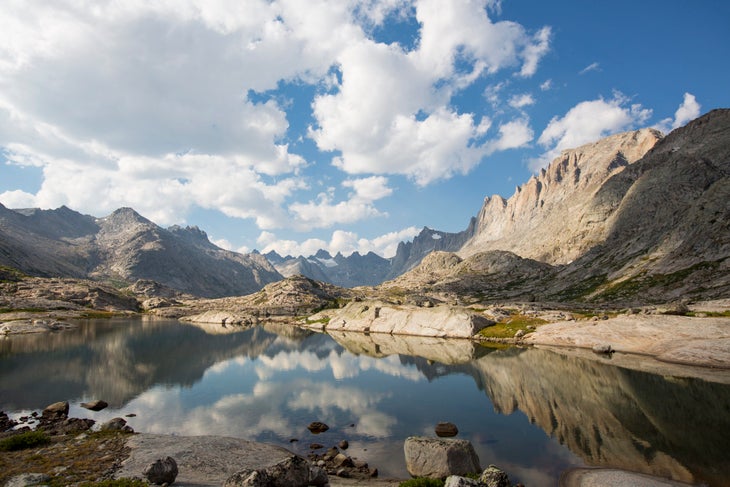 a lake in the foreground with granite peaks rising behind it