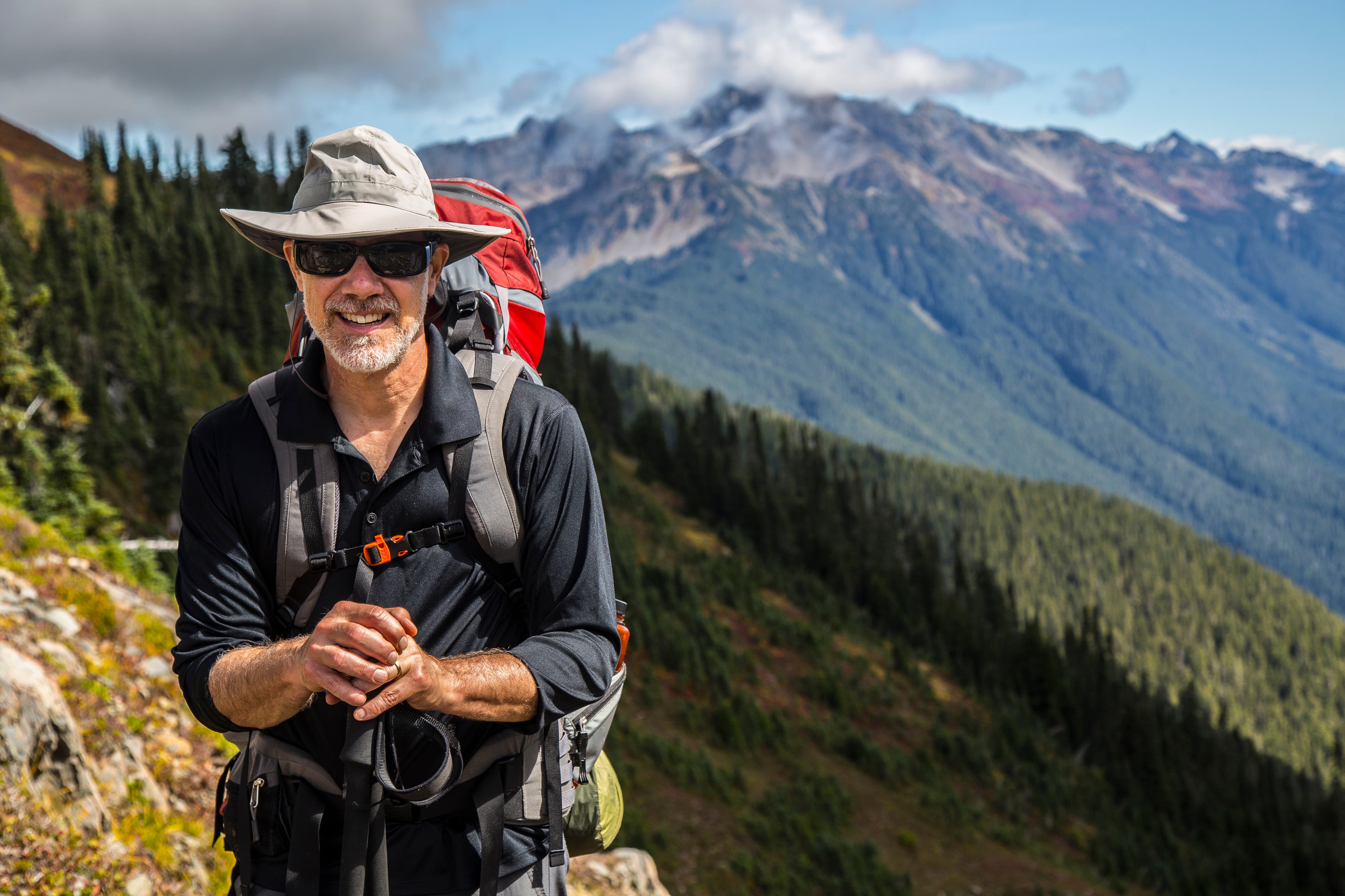 shutterstock_1026295264 Man standing with hiking poles moutain background
