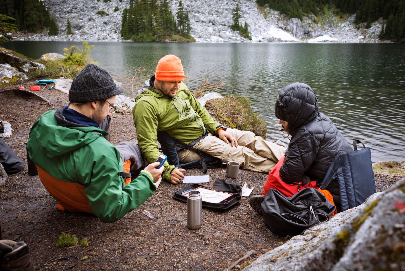 Friends playing board games while sitting at lakeshore
