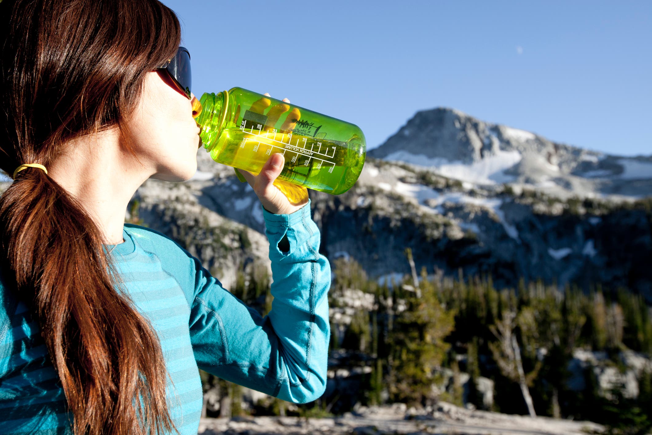 A woman sips from a water bottle while backpacking in the Wallowa mountains.