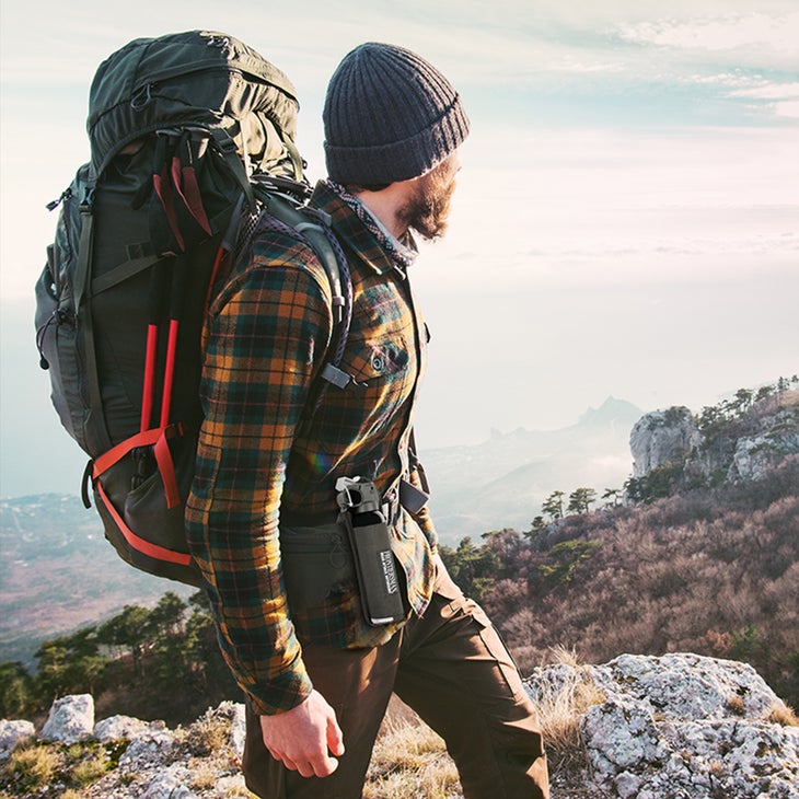 bear-spray-holster Man in flannel shirt and backpack wearing bear spray in a hip holster.