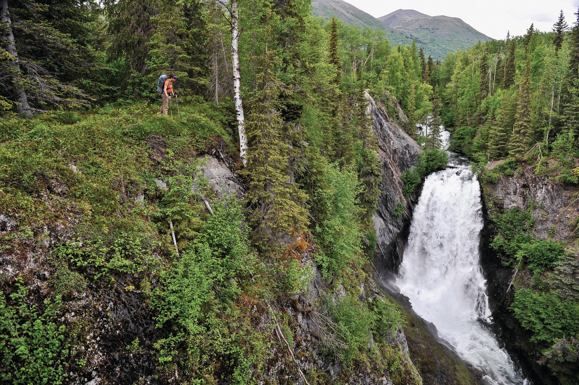 hiker by waterfall in forest