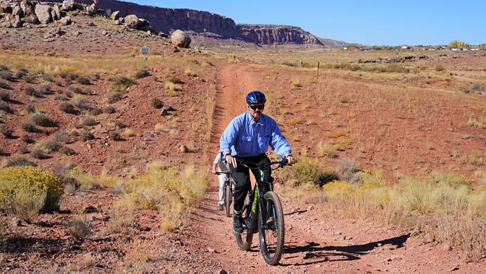 "William Perry Pendley riding a bike in the desert"