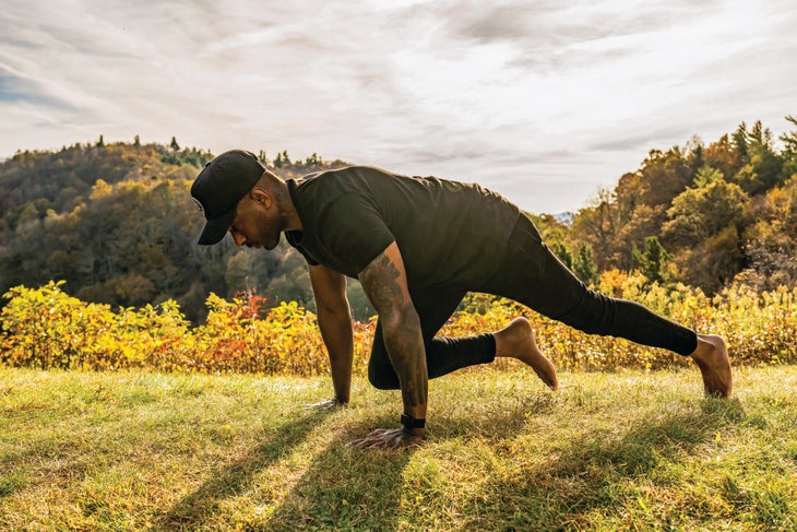 "Athlete in grassy field doing mountain climbers"