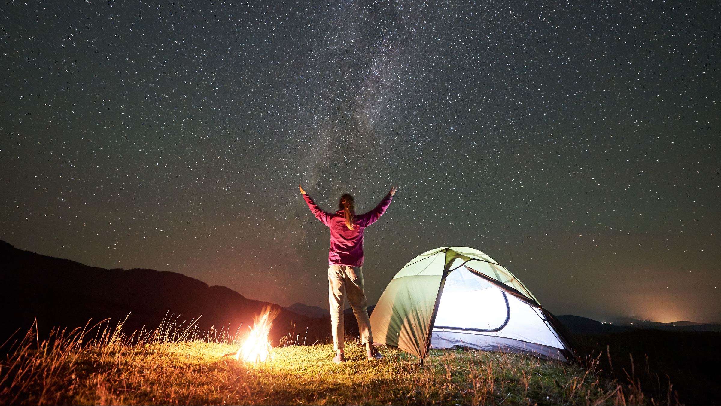 Man marvels at stars next to campfire