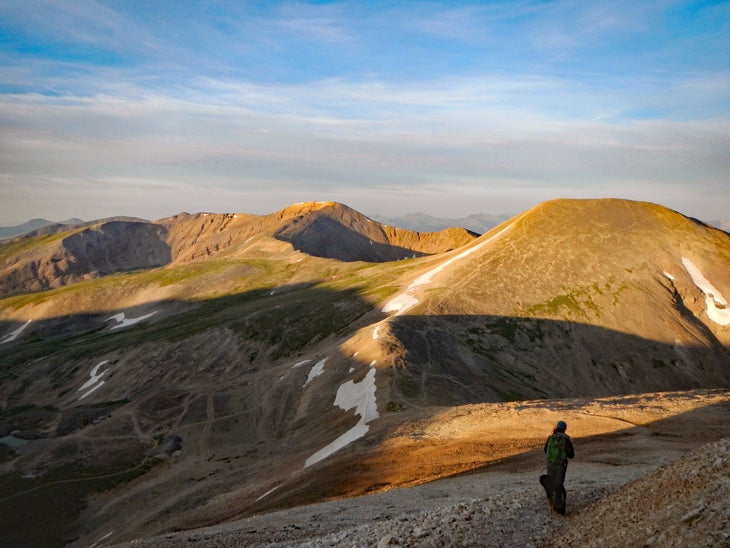 Woman and dog descending mountain in morning sunlight