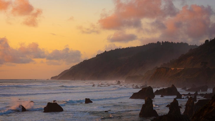 the ocean on the left with waves rolling in to a hilly coastline on the right