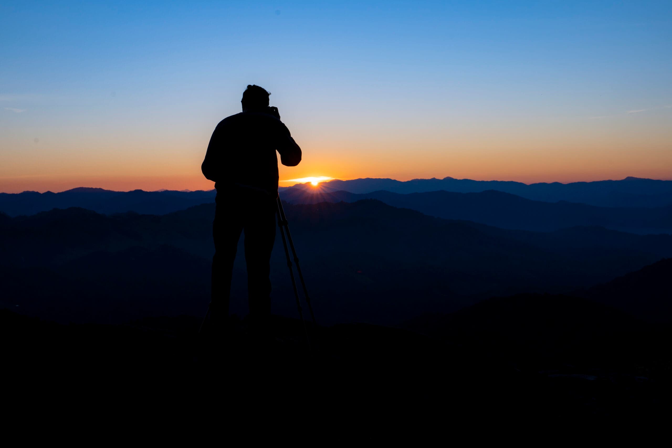 Sugarloaf Mountain, Best Sunrise Hikes A hiker is silhouetted by the rising sun as it makes its first appearance in the morning sky.