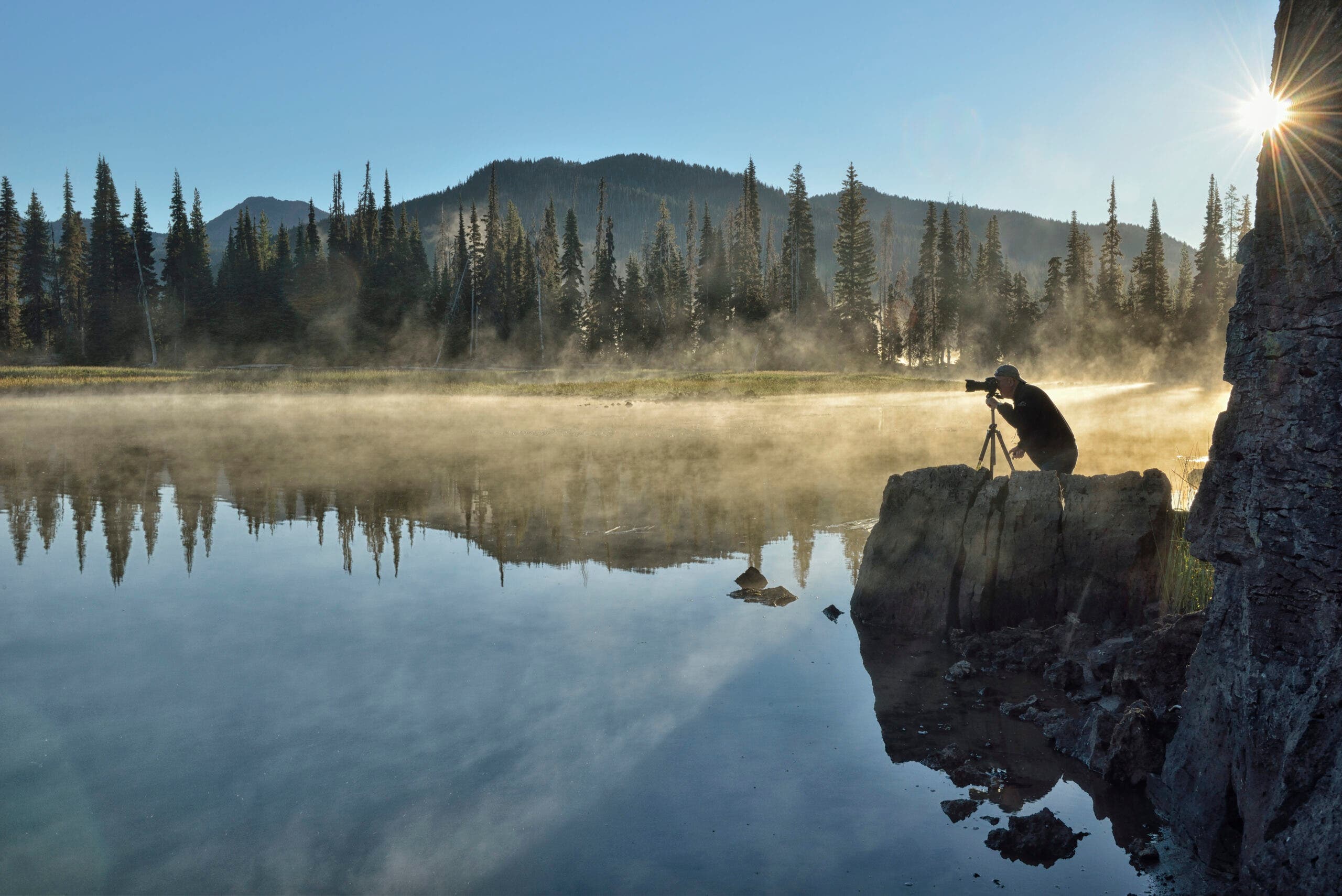 Sparks Lake, Central OR Photographer with tripod and camera catching the early morning light reflecting off Sparks Lake in Central Oregon.