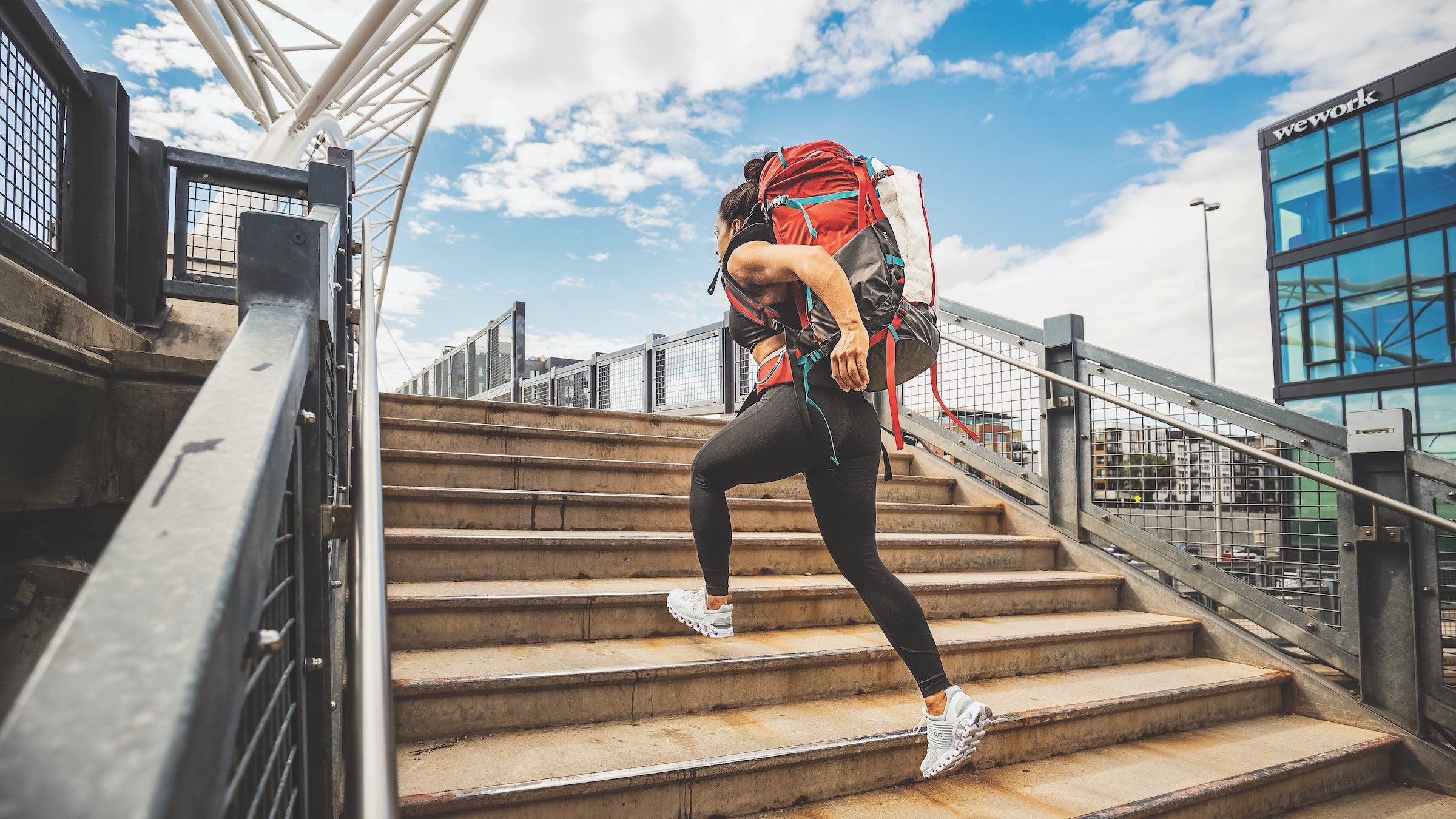 A woman with a backpacker running up stairs in a city.