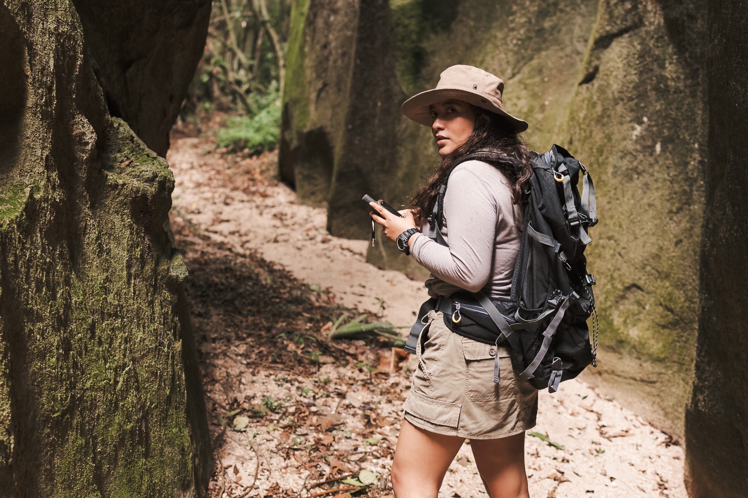 A female hiker in a canyon holding a GPS device.