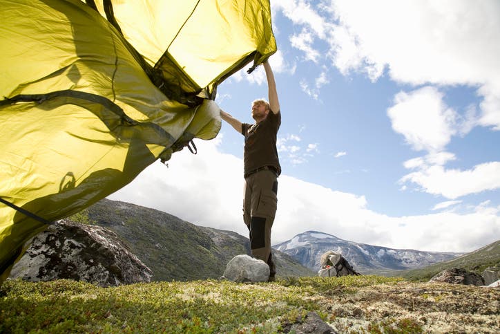 a man laying his tent on the ground