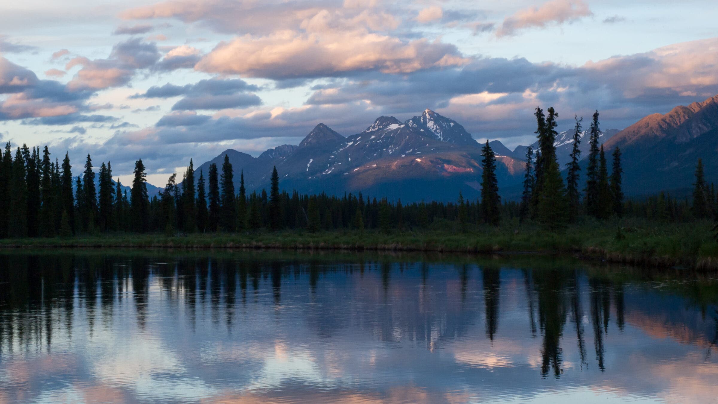 a lake with a mountain behind it at dusk; the mountain is reflected in the water
