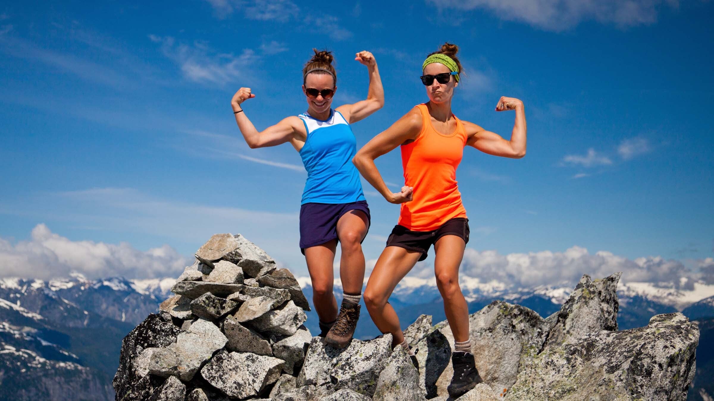 two female hikers flex after a summit