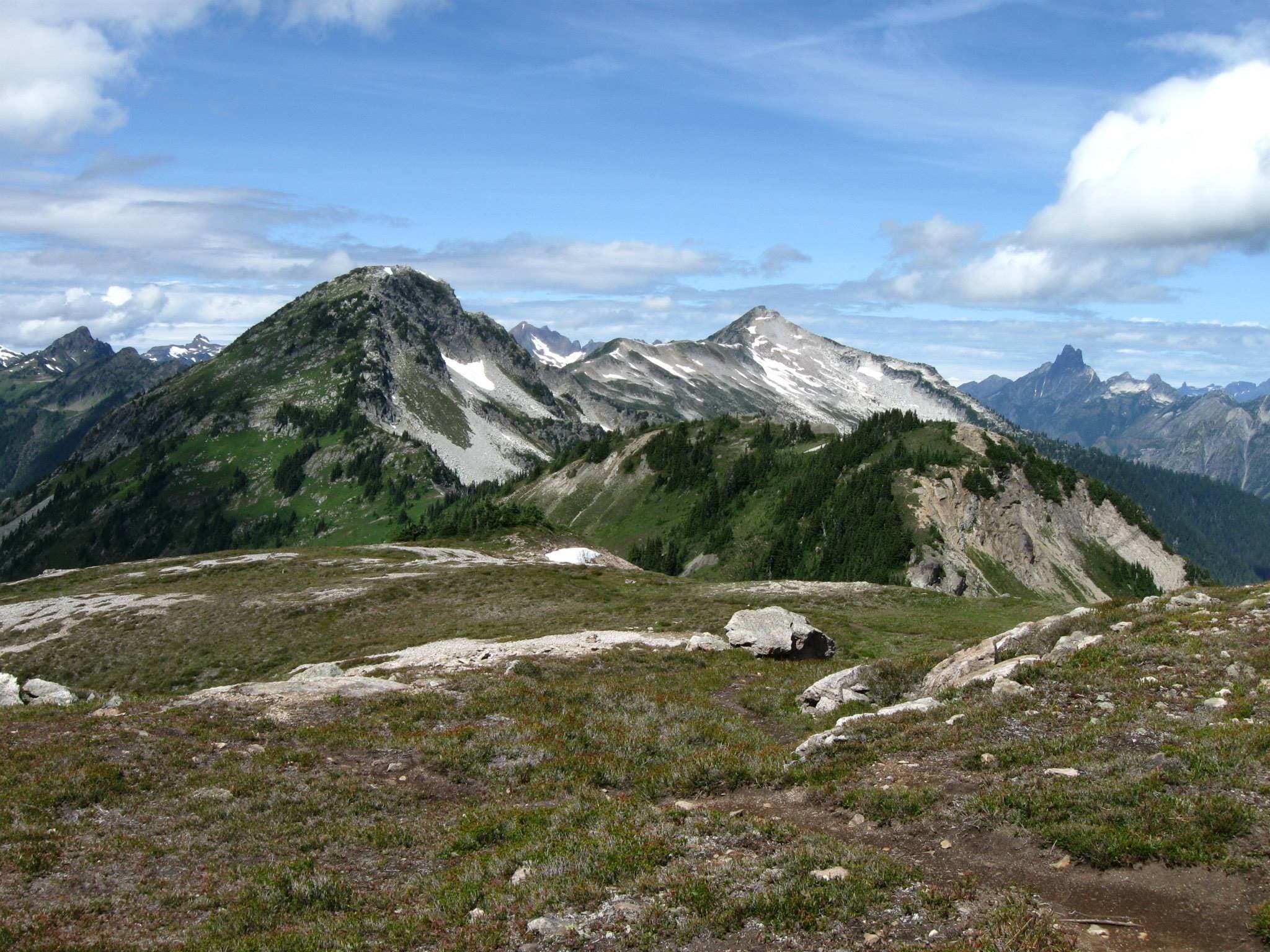 a flat meadow with a ridgeline rising to peaks in the distance
