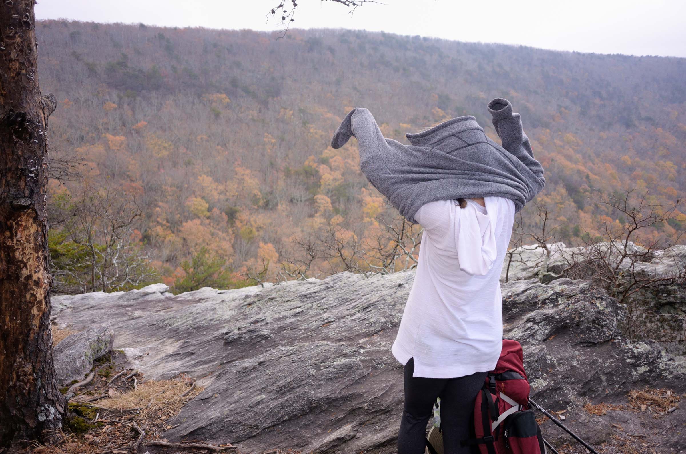 hiker pulling on sweater