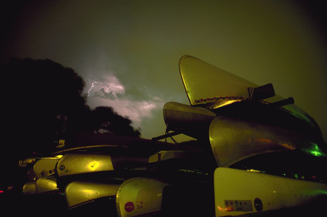 Lightning lights up the sky over a stack of canoes