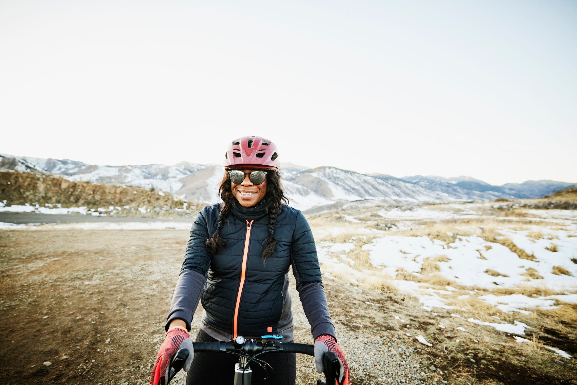 Portrait of smiling female cyclist riding gravel bike at sunset on winter evening