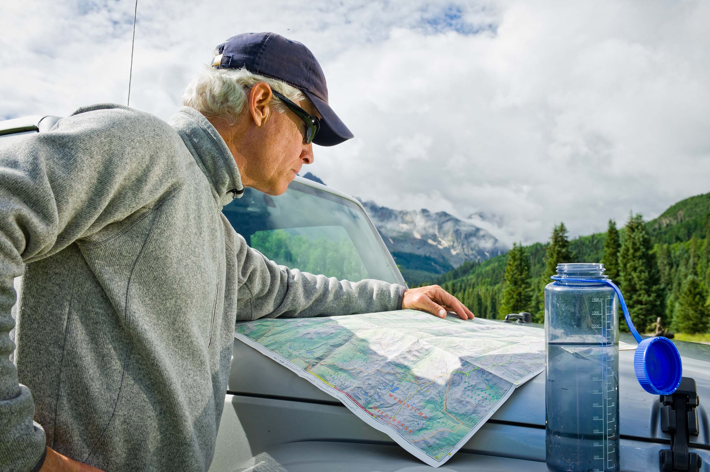 man reading topo map on car hood
