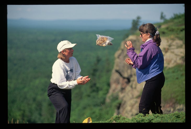hikers tossing bag of gorp