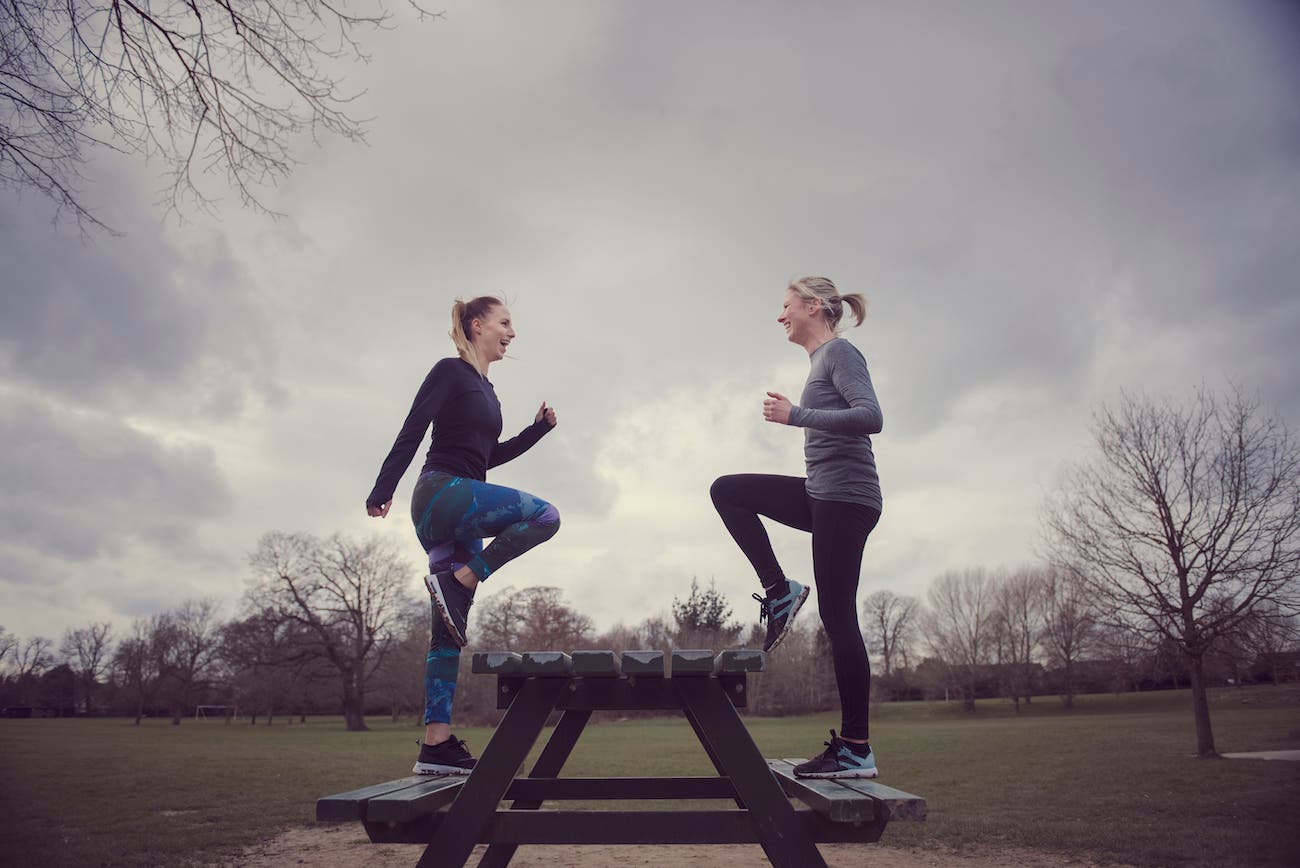 Full length side view of women doing step ups on picnic bench