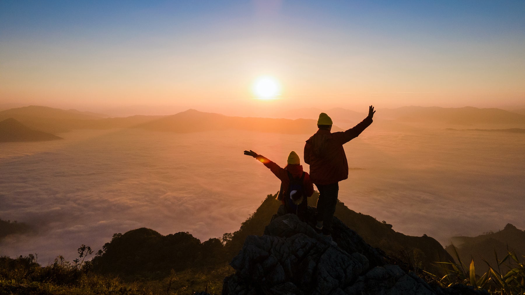 friends posing on a mountaintop at sunrise