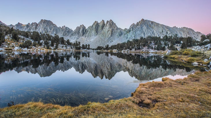 Snow-capped mountains reflecting on to Kearsarge Lake in Inyo National Forest.