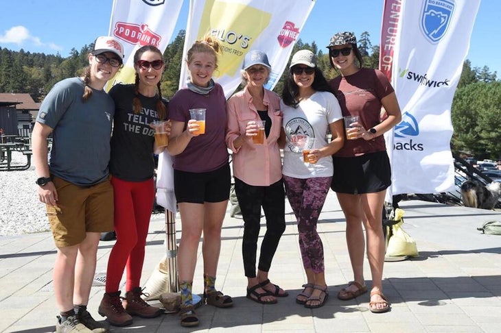 six female hikers standing and holding drinks