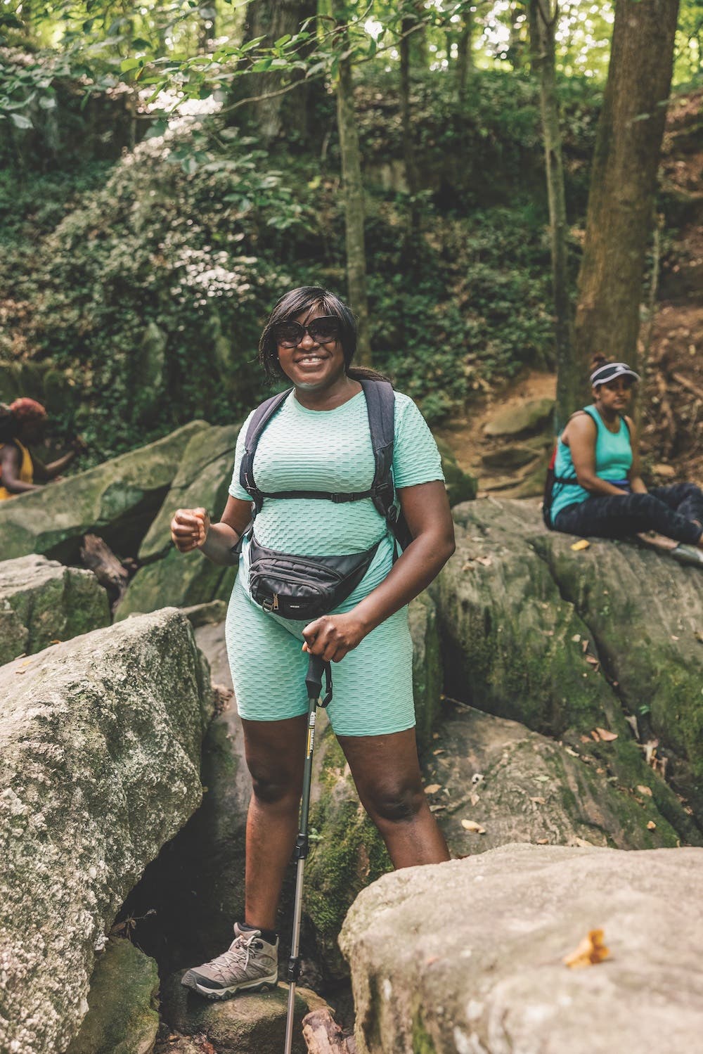 woman smiles to camera with trekking poles in hand