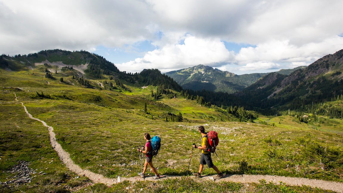 A young couple backpacking along a trail in the Olympic National Park.
