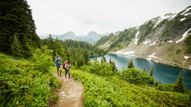 Father and son hiking on mountain trail above alpine lake