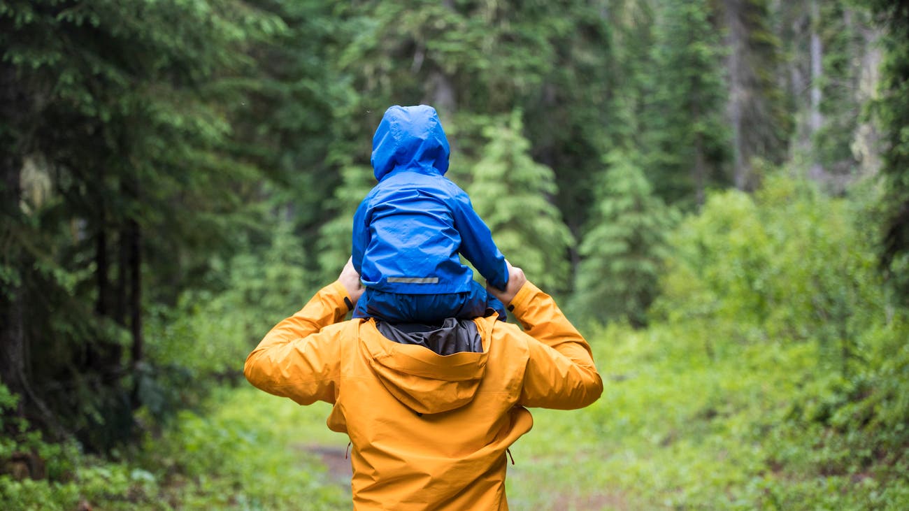 Rear view of Father carrying son on shoulders during a hike.