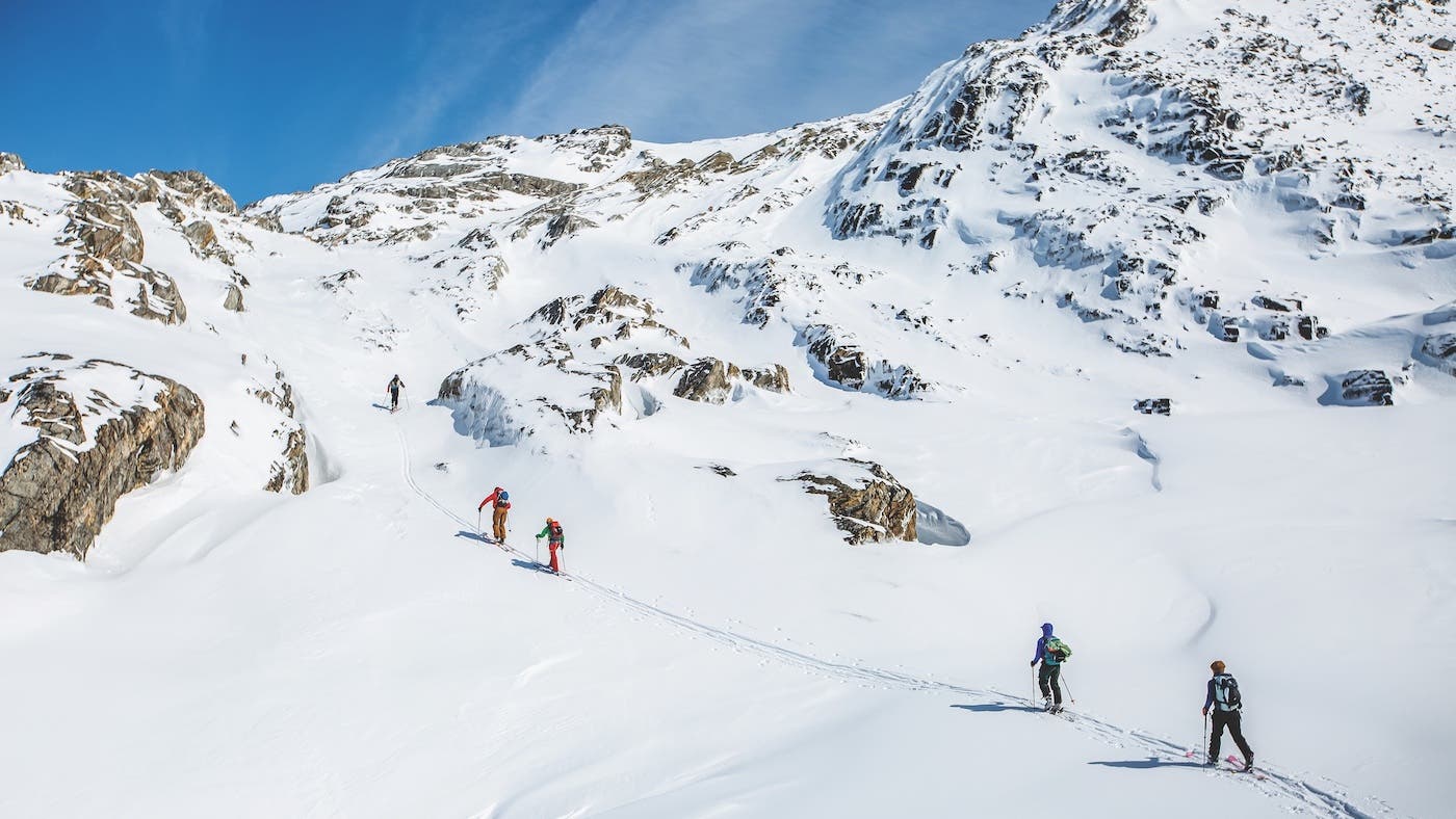 many people skiing uphill on snowy mountain