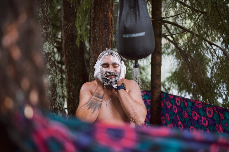 Adult male is taking a bath with a water bag outdoor shower