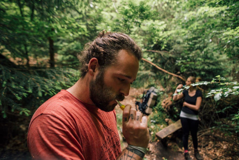 man and woman brushing teeth in backcountry