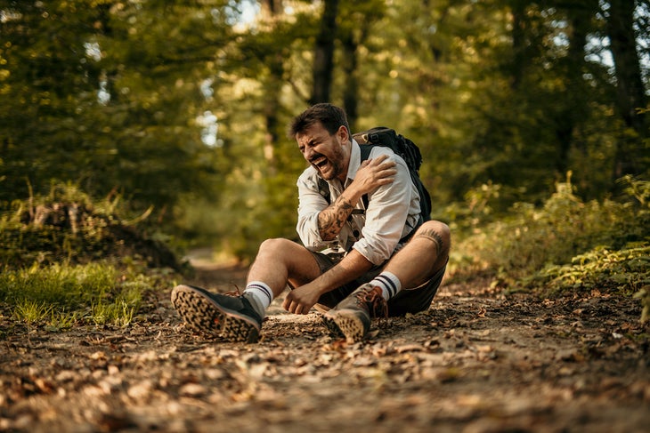 man has an arm and shoulder injury while trekking/hiking in the mountain