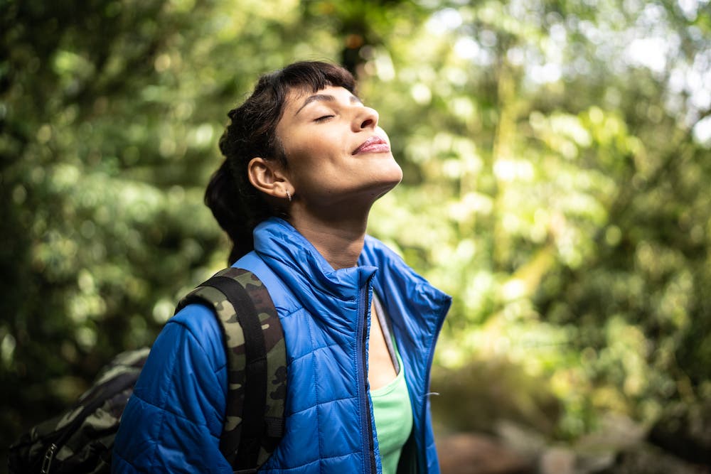 Young woman breathing pure air in a forest