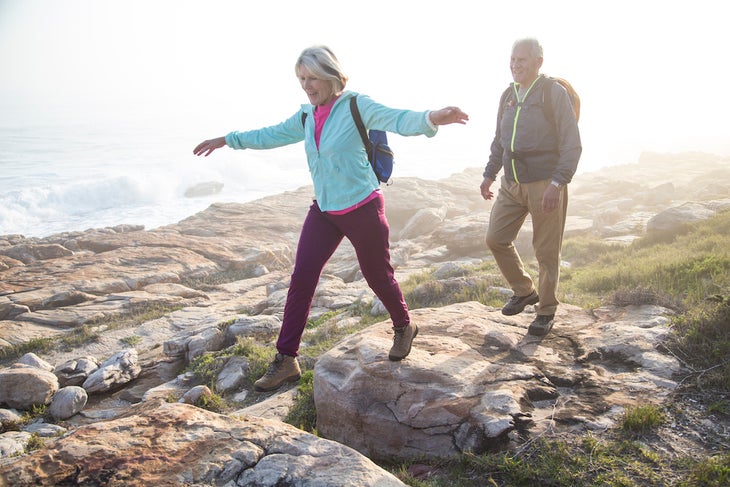 Senior couple hiking outdoors together on a coastal path near the sea