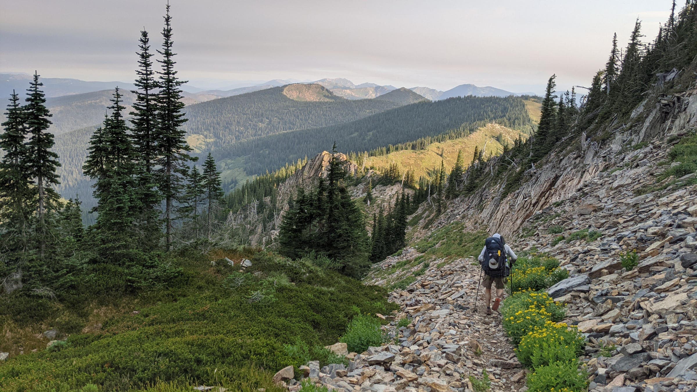 a hiker descends a rocky trail in the mountains