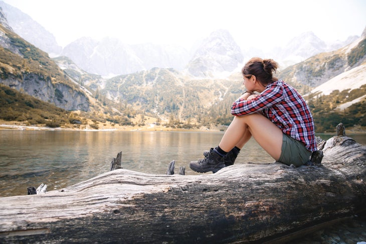 Hiker sits on a log looking out over a lake