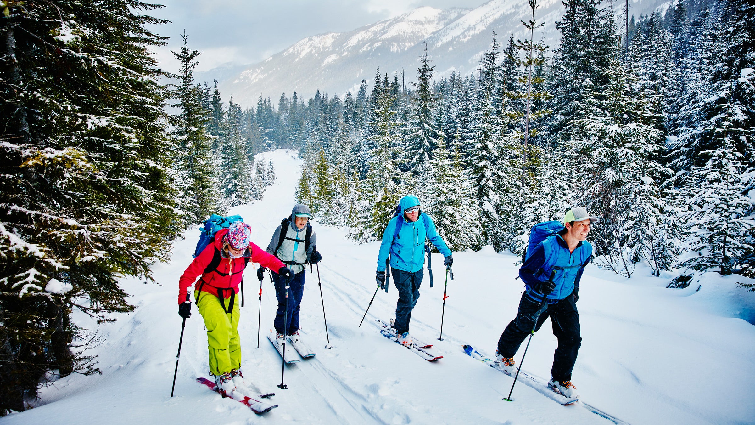 Smiling friends ascending mountain during ski tour