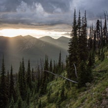 Trail in mountains with sunbeams shining through clouds