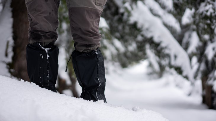 Hiker standing in snow wearing gaiters
