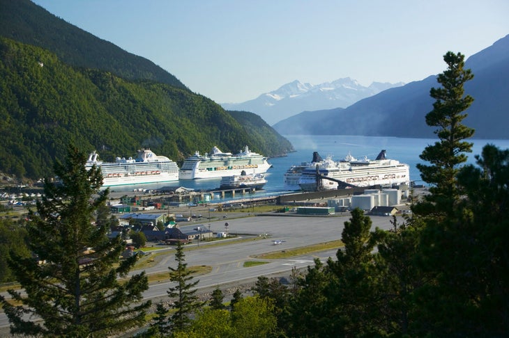 Cruise ships anchored in a port with mountains behind. 
