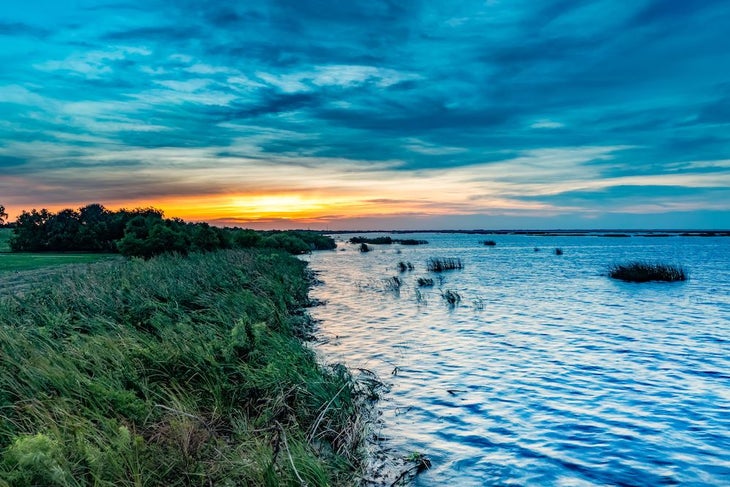 An aerial view of Lake Okeechobee surrounded by lush greenery at sunset in Florida, the United States