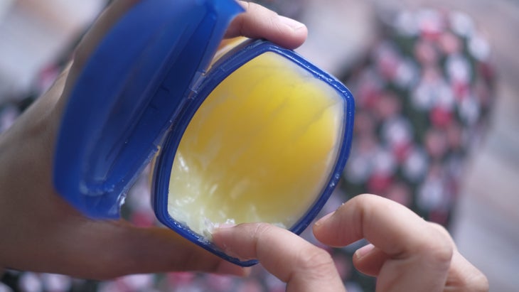 Person dipping finger into a container of Vaseline