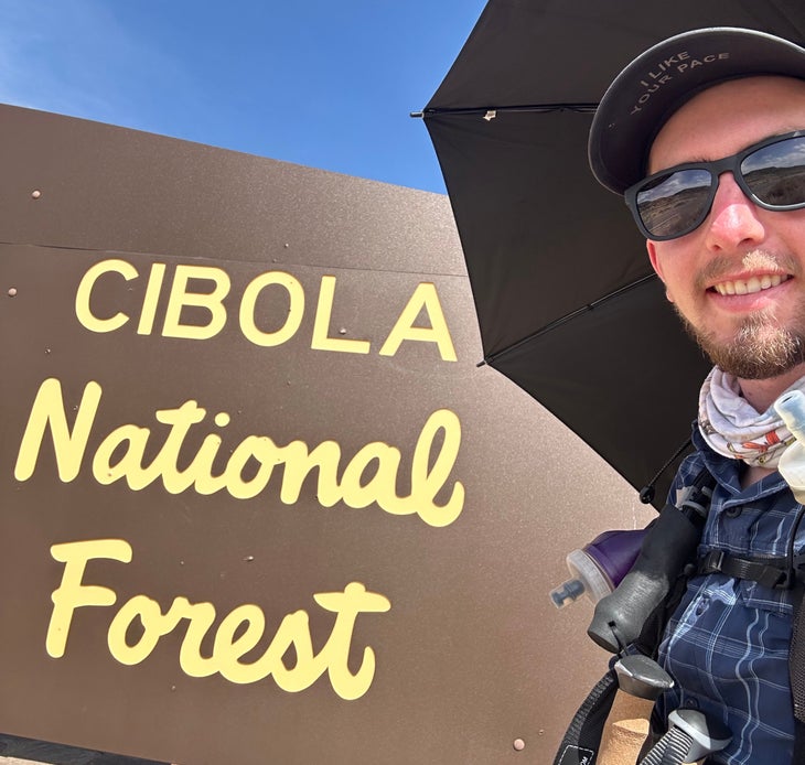 Hiker next to Cibola National Forest sign